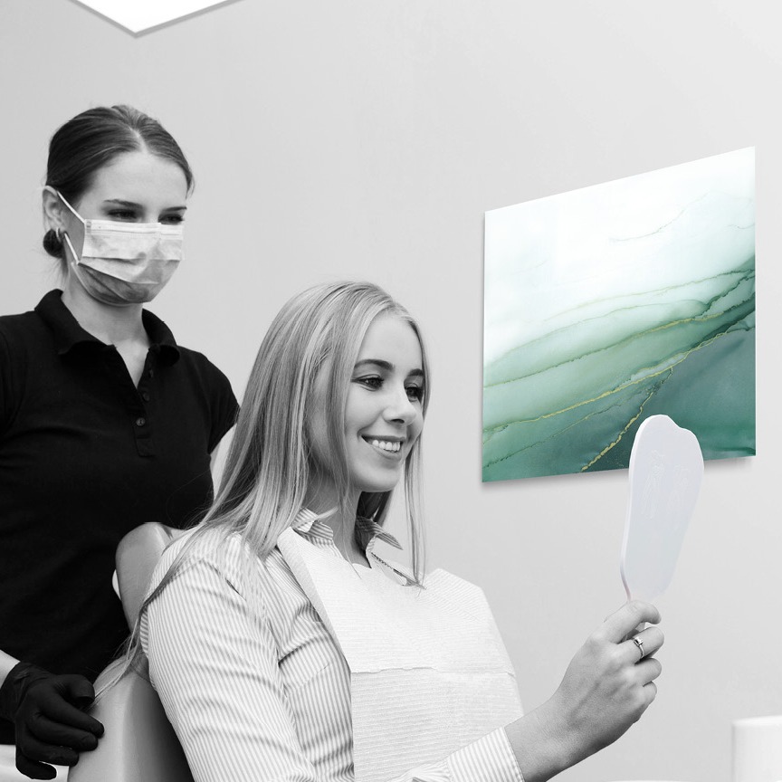 Zahnarzt mit Patientin in Praxis mit abstrakter beruhigender Kunst